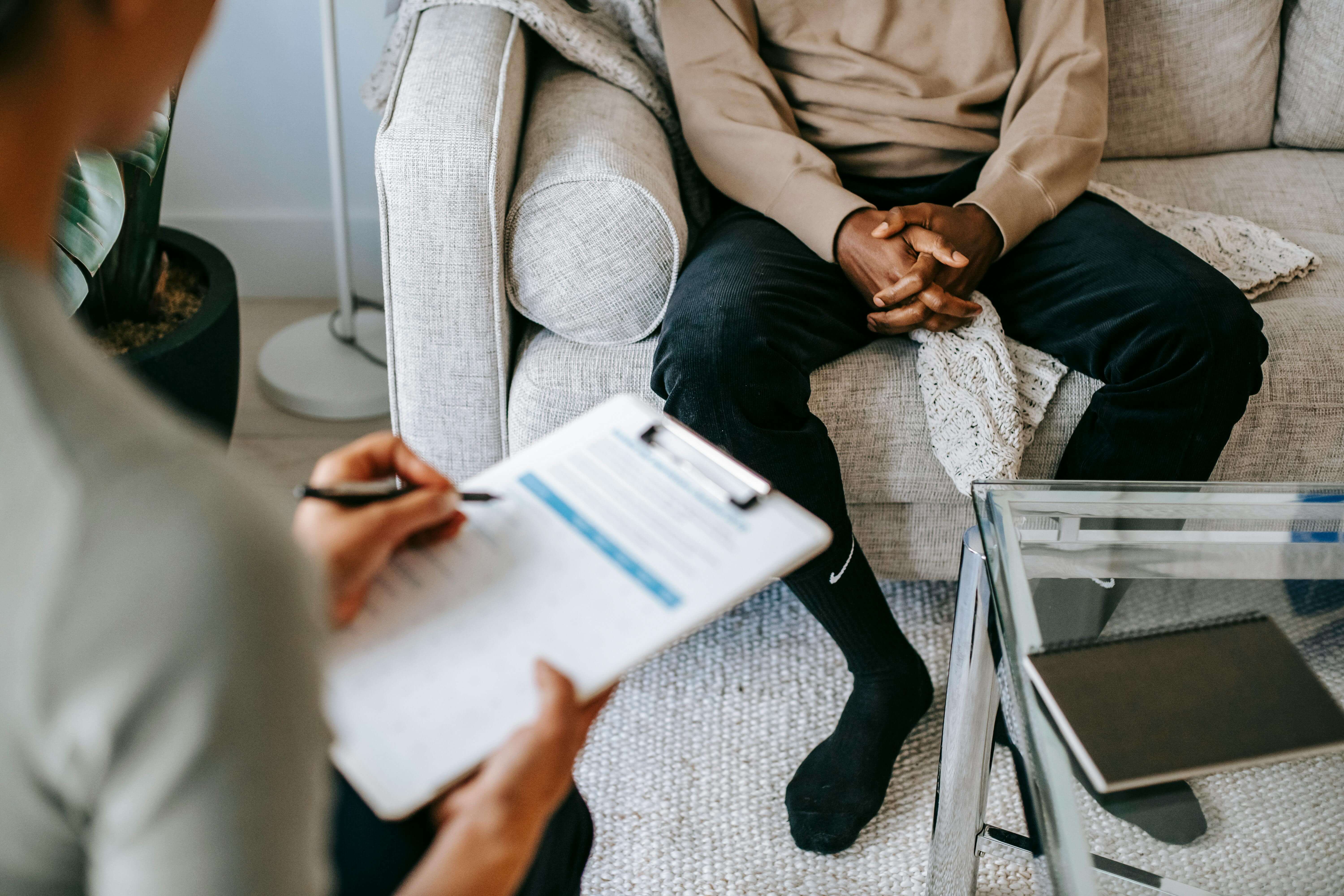 Man sitting on a couch speaking to a therapist. If you're struggling with depression as a man, begin to heal from your symptoms with the support of men's therapy in Kenosha, WI.