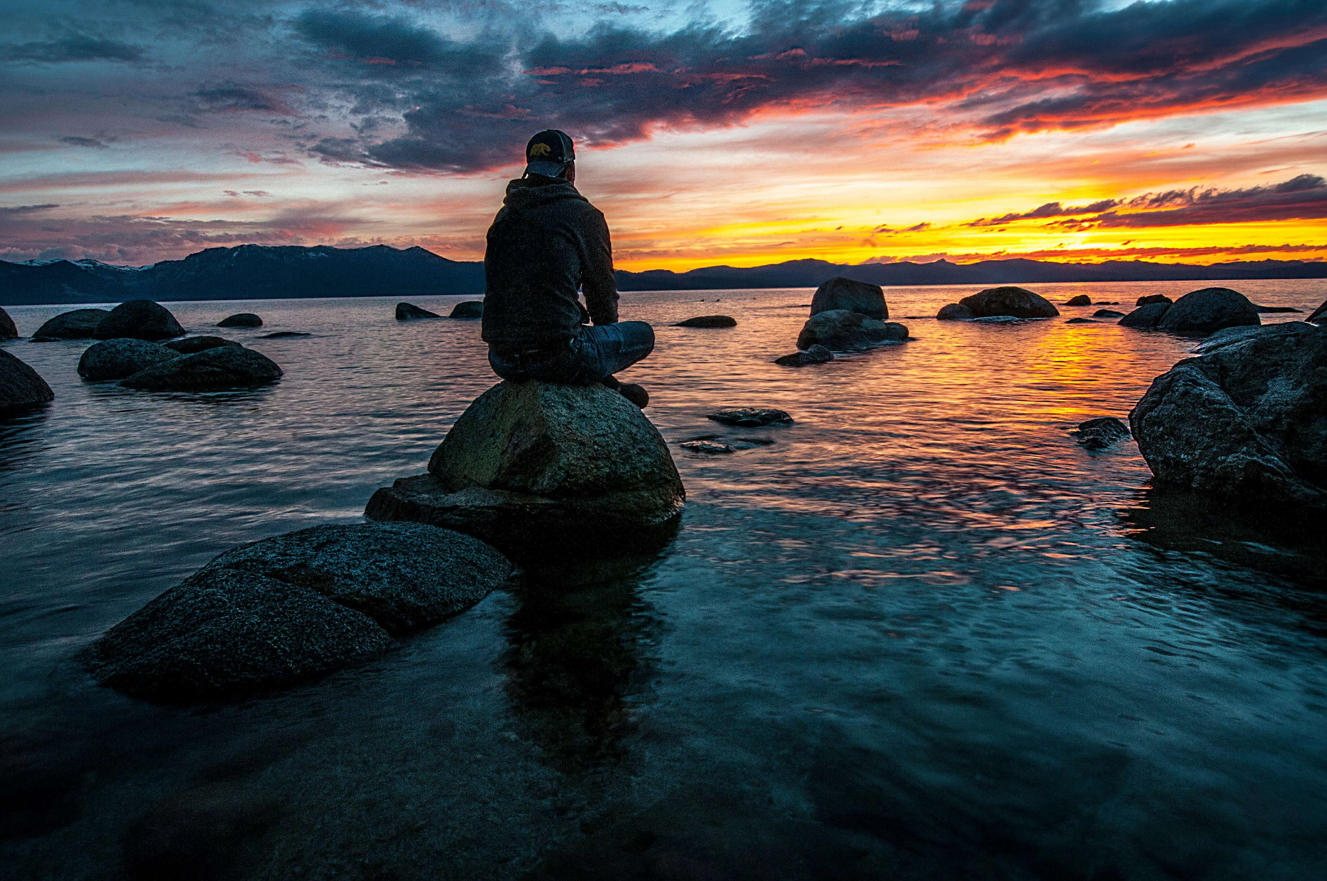 man on rock | mens therapist in mount pleasant, wi | men and mental health | mens therapist | Mount Pleasant | Burlington | Lake Geneva Man sitting on a rock by the water at sunset, finding calm and reflection in nature. Discover how men’s therapy in Mount Pleasant, WI can help fathers process pain, heal, & rebuild strength.