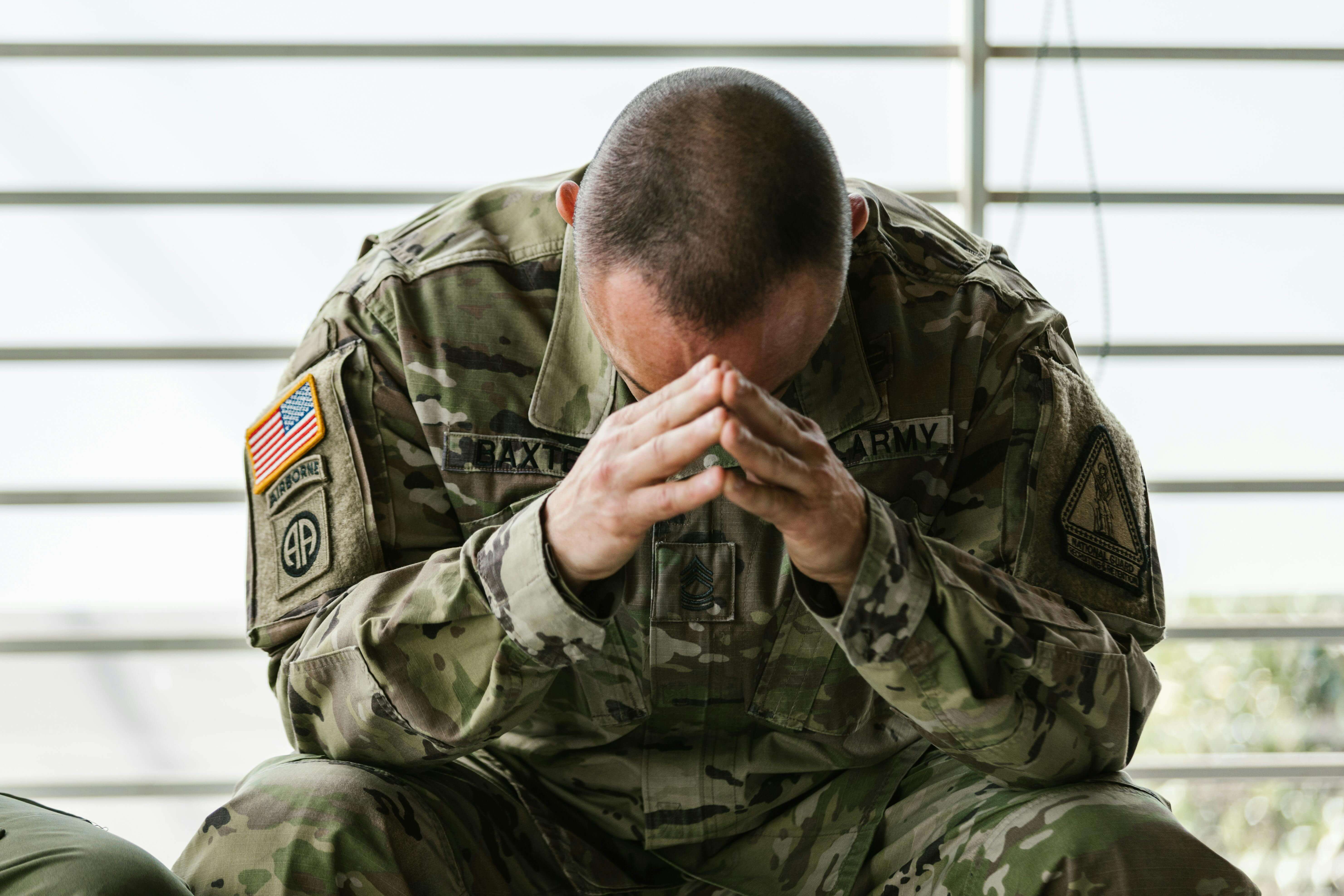 military | mens therapist in milwaukee, wi | men and grief | mens therapy | Mount Pleasant | Burlington | Lake Geneva A man in military uniform sitting with his head bowed and hands clasped, appearing overwhelmed or distressed. Men carrying emotional weight from loss or trauma can begin healing through men's therapy in Milwaukee, WI with compassionate guidance.