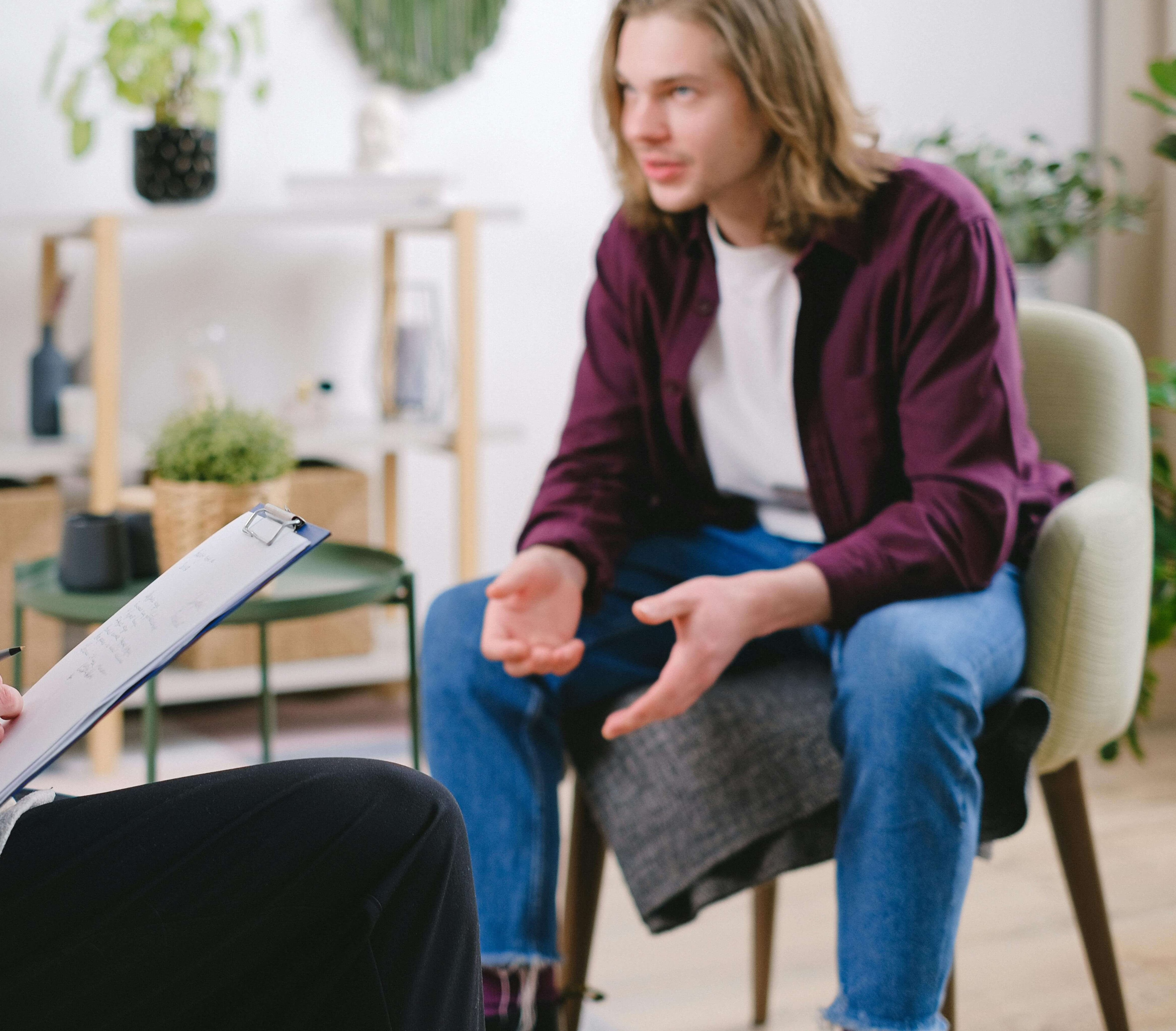 man in therapy | mens therapy in racine, wi | mens therapist | men and mental health | Mount Pleasant | Burlington | Lake Geneva Man sitting in a chair having a conversation with a therapist holding a clipboard. Break free from the mental health challenges you face with the support of a men's therapist in Racine, WI. Start building your confidence and thriving soon.