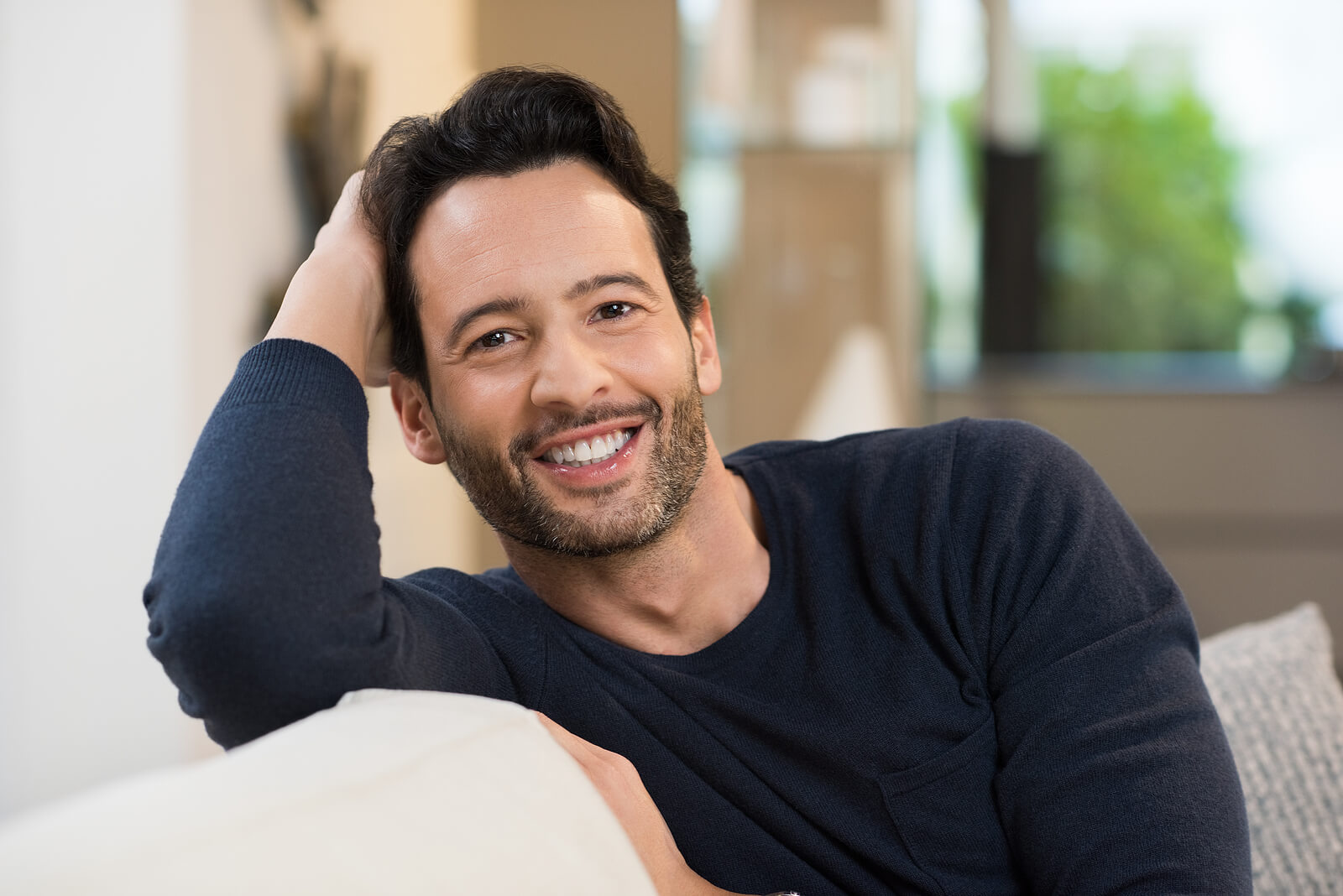Smiling man relaxing on a couch, appearing calm and grounded in a comfortable living space. Rediscover a sense of ease and emotional balance as you work through past trauma with men's therapy in Milwaukee, WI, guided by a skilled men’s therapist.